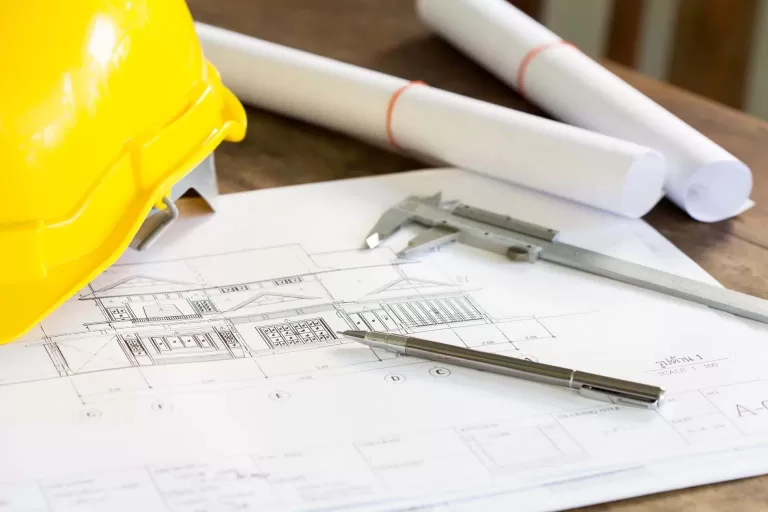 Construction plans with yellow helmet drawing tools